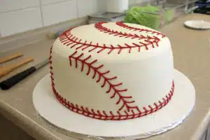 A beautifully decorated baseball cake with red stitching on white fondant, perfect for a sports-themed party.