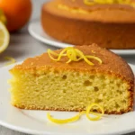 Moist olive oil citrus cake slice with lemon zest and powdered sugar.